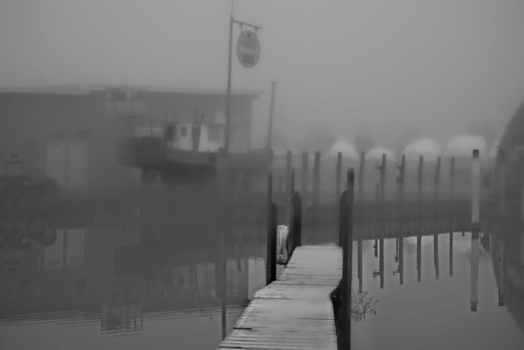 a foggy image of a boat stored on land for the winter with barely visible additional boats in the background