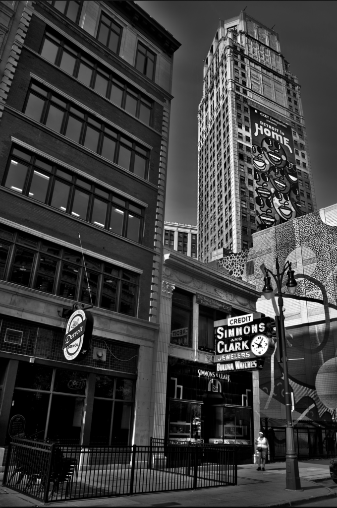 a women walking with a detroit skyscraper in the background